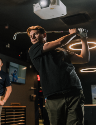 Man swinging a golf club at Five Iron Golf simulator