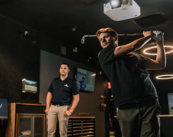 Man swinging a golf club at Five Iron Golf simulator